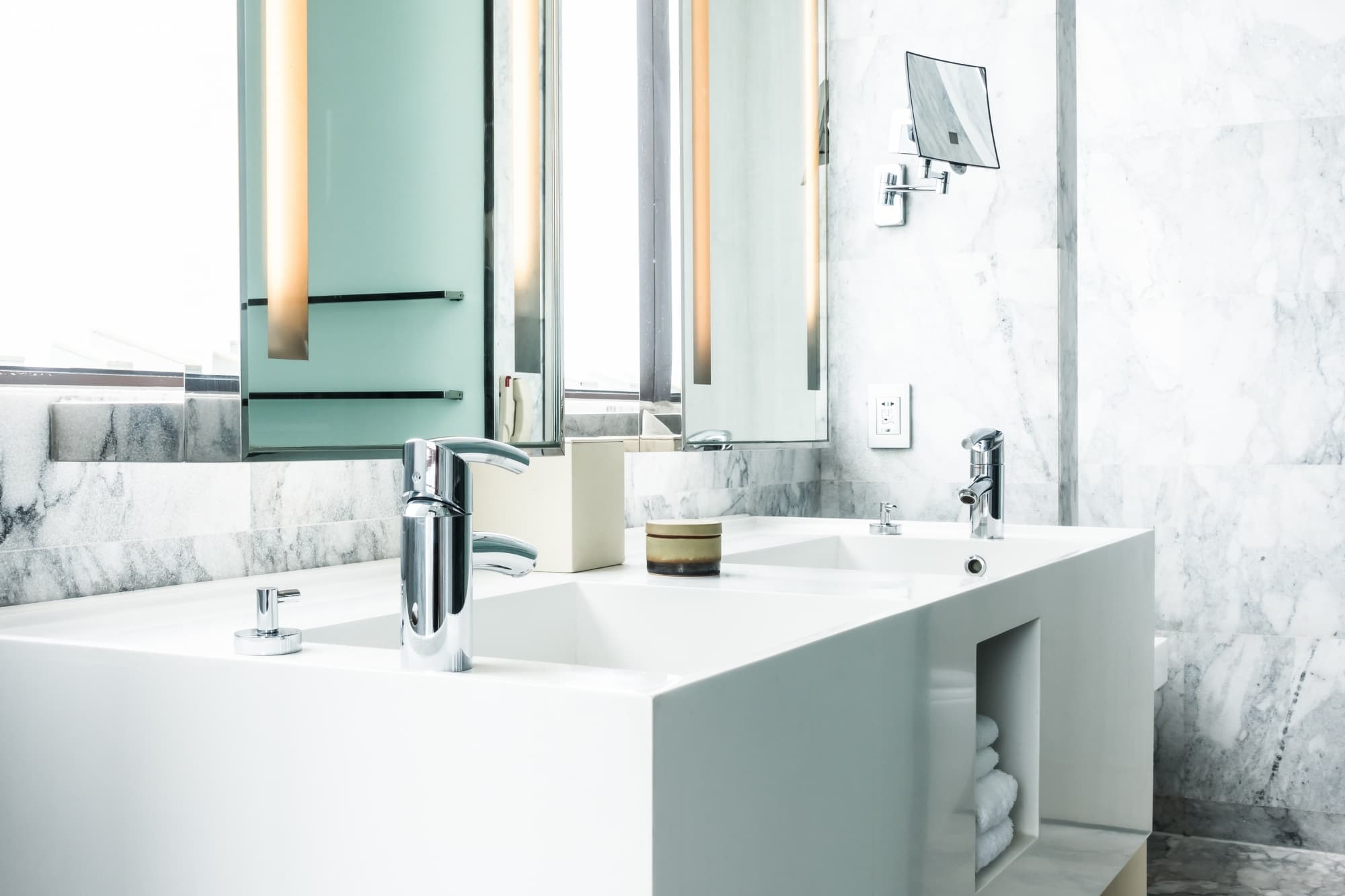 Mermer kaplı duvarın önünde iki krom bataryalı çift lavabo